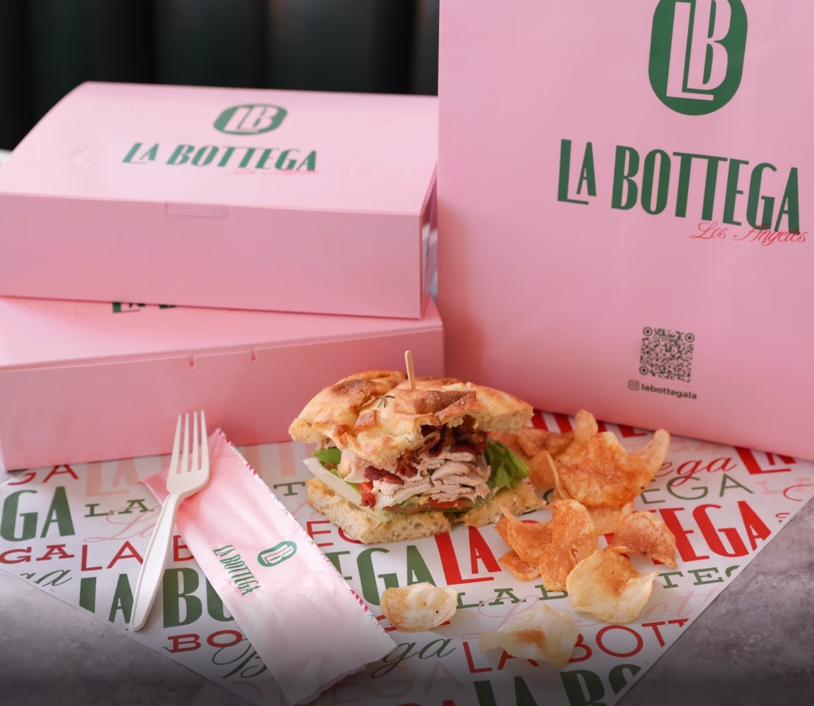 Pink Custom Takeout Boxes With QR Code, Branded Cutlery Sleeve and Gourmet Chicken Sandwich With Crispy Chips Highlighting Customizable Café Packaging For Delivery